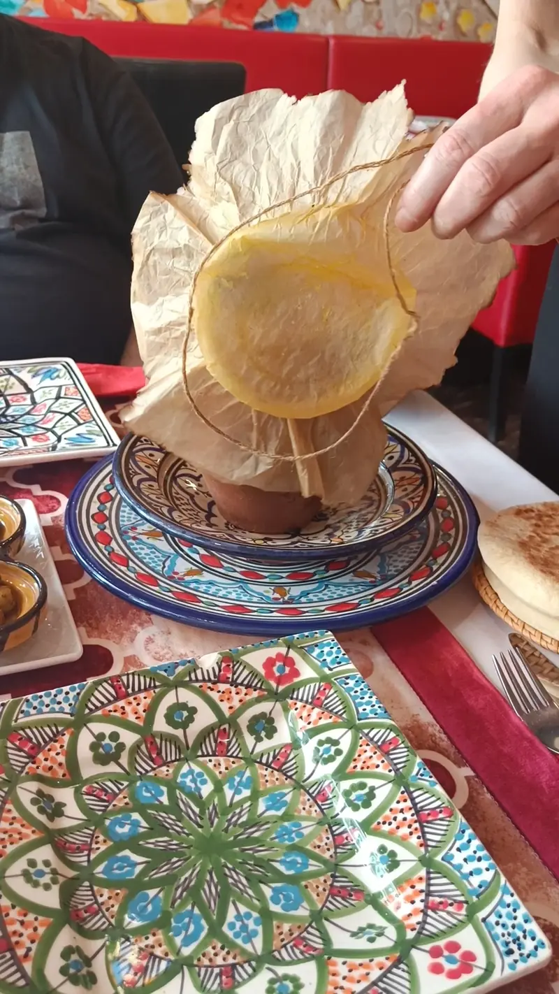 Kelnerka odwiązuje papier z glinianego dzbana tanjia